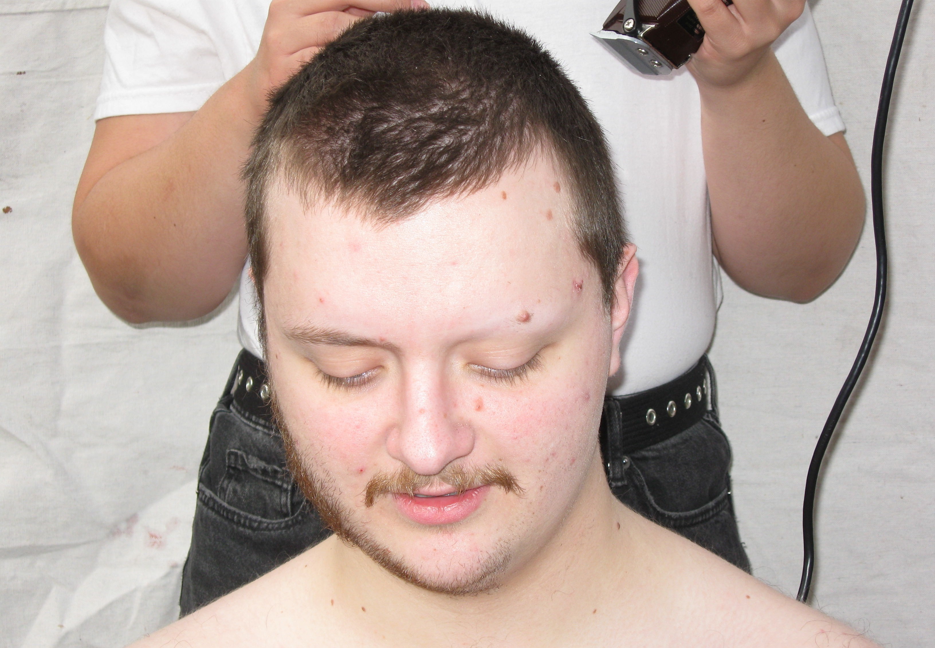 Daughter Lotus looking down, getting prepared to get the hair on his head shaved for the cover of his EP Music For Posing.